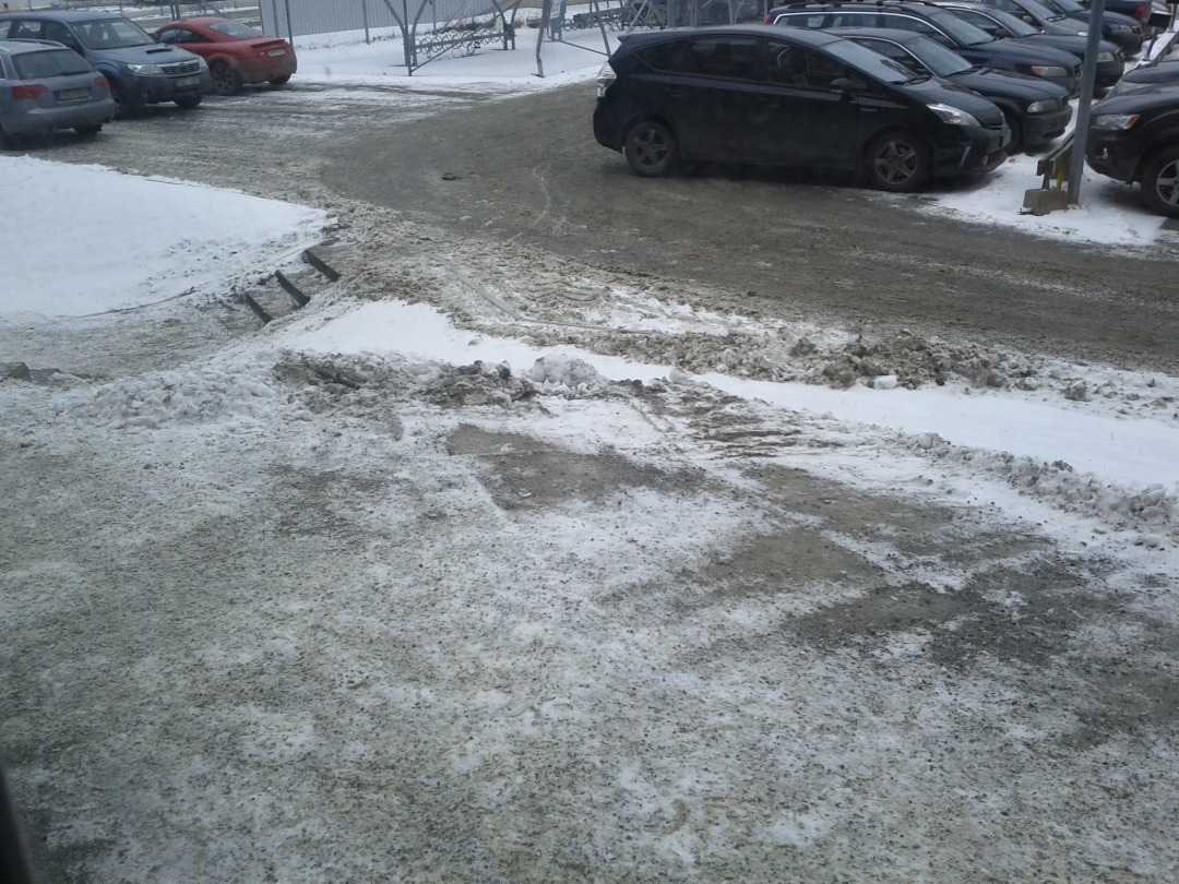 Saída de pedestres de um estacionamento onde a neve já está toda suja e marrom.