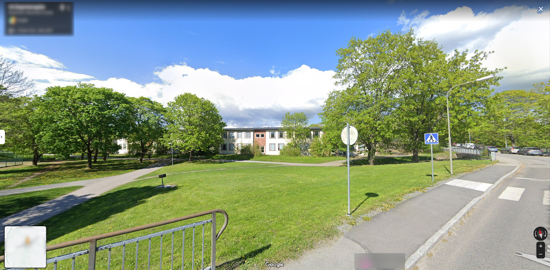 Foto do Google Maps mostrando outro local de uma escola.  Mas como fica no meio do parque não é possível ver detalhadamente.  Aparece na foto um gramado grande, árvores e um prédio comprido de 2 andares ao fundo.